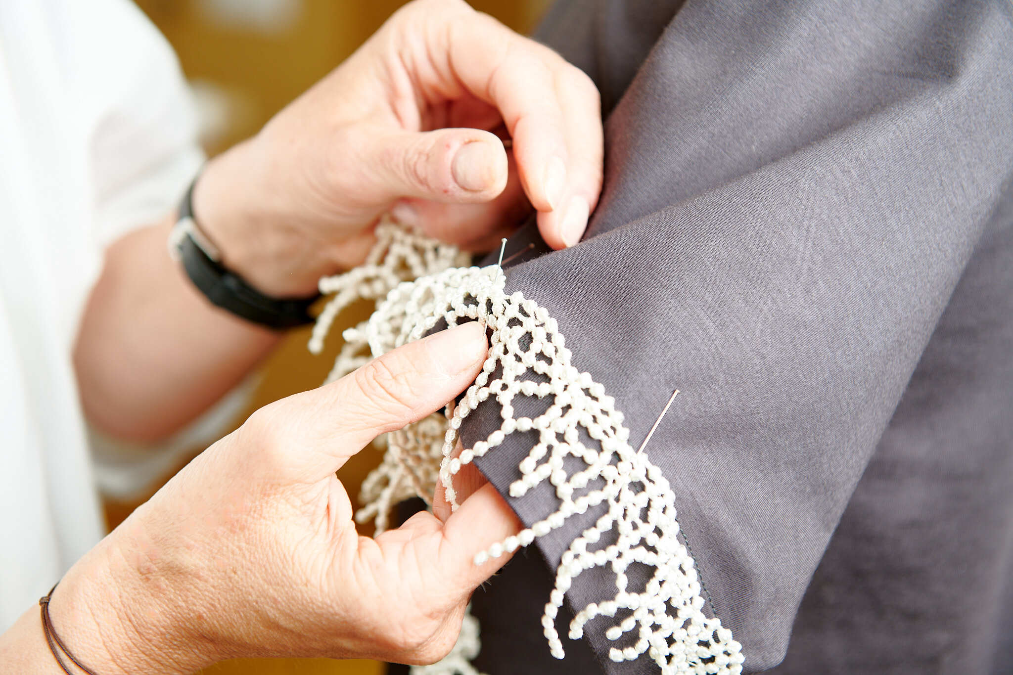 Spitzen werden von Hand an T-Shirt-Ärmel angenhäht